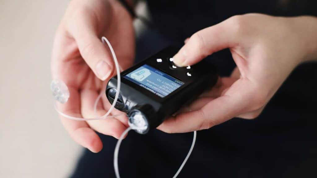 Closeup shot of a woman's hands holding a closed loop insulin pump.